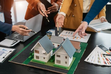 Business people working on a model of a house. Loan Signing Agent assisting in real estate transaction.