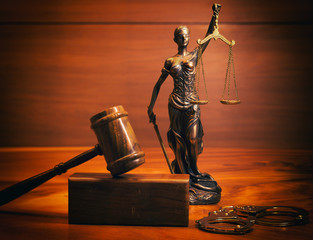 Law and justice symbolized by a lady justice statue and a gavel on a wooden table, representing the concept of Filing Affidavits.
